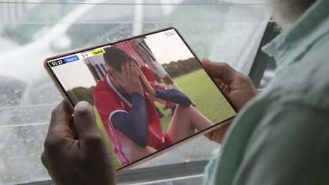 Video-Einer-Person,-Die-Auf-Der-Couch-Sitzt-Und-Sich-Ein-Fußballspiel-Auf-Einem-Tablet-Ansieht