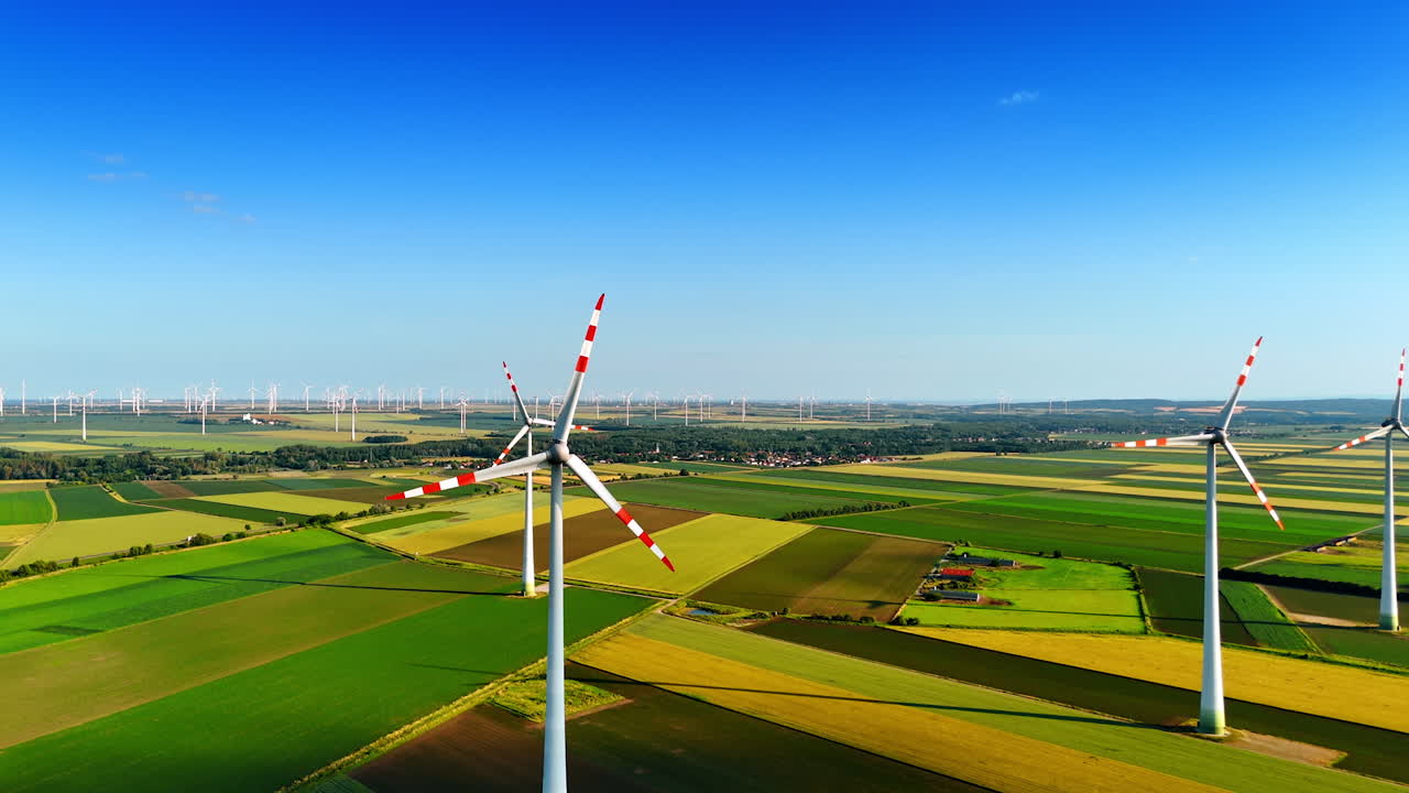 Spectacular green fields in the picturesque countryside. Windfarms produce green energy. Aerial view
