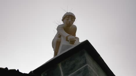 Estatua-De-Piedra-De-Un-Niño-Encima-De-Una-Antigua-Iglesia-Medieval-Gótica