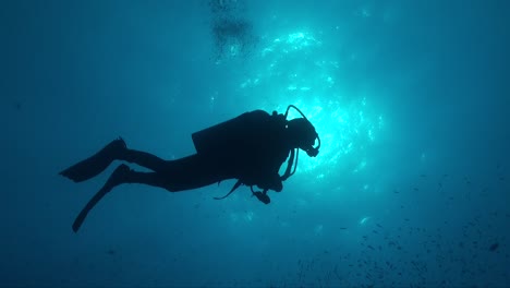 silhouette of a scuba diver in full equipment below the ocean surface