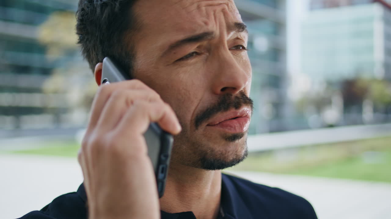 스트레스를 받은 남자가 드폰으로 비즈니스 외부 클로즈업으로 전화합니다. 화가 난 상사가 말합니다.