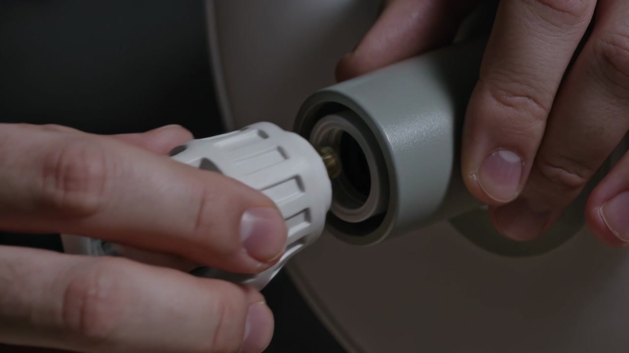 Holding lit bulb cuffed hands unscrewing seating white LED adapter in lamp socket home to upgrade