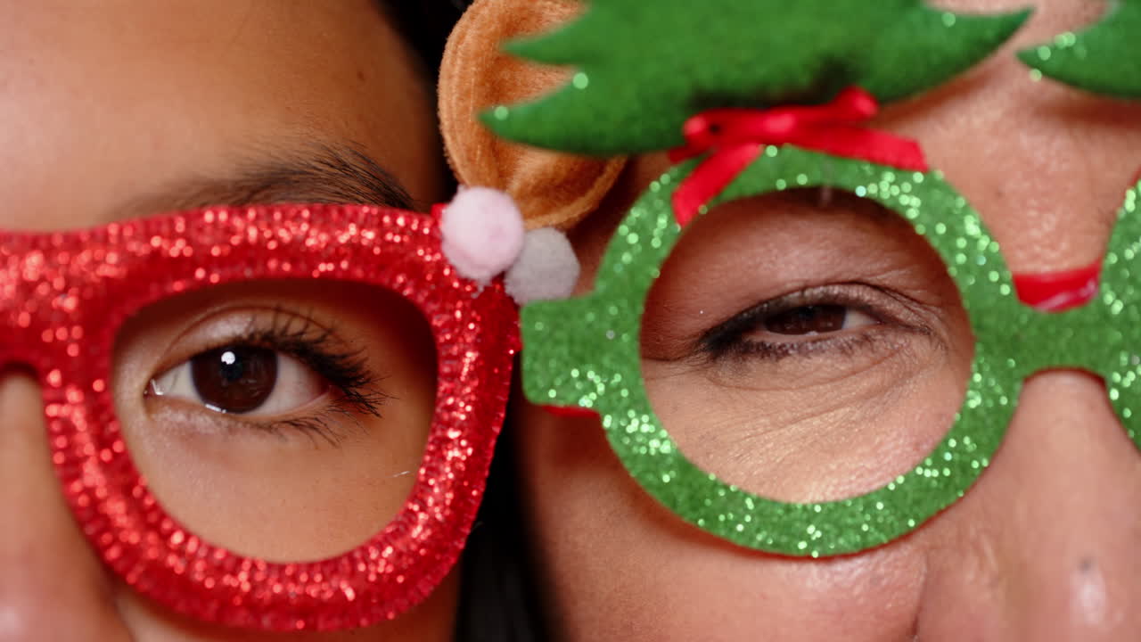 At christmas, wearing festive glasses, grandma and teenager celebrating together happily