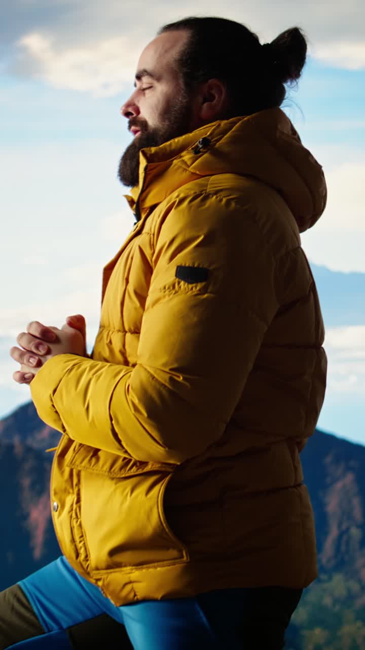 Uomo con giacca gialla in piedi sulla cima della montagna che guarda il panorama