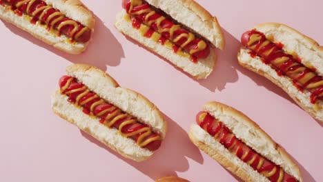 Video-of-hot-dogs-with-mustard-and-ketchup-on-a-pink-surface