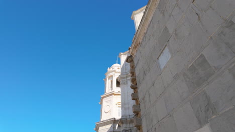 A-street-level-view-of-a-grand-building-with-a-stone-facade-and-a-dome,-likely-a-church-or-cathedral,-set-against-modern-traffic-and-urban-life,-showcasing-the-blend-of-old-and-new