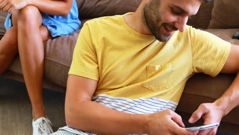 man text messaging and woman peeking into his mobile phone from behind
