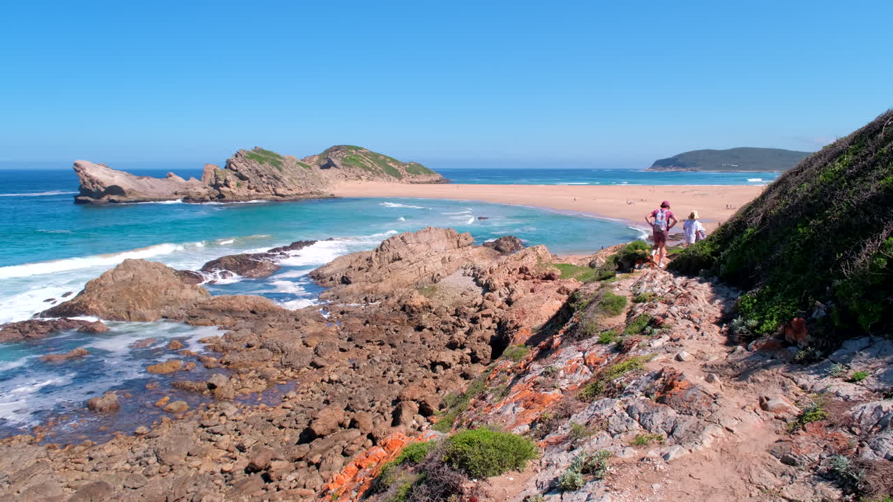 Persone fanno escursioni sul sentiero circolare di Robberg con vista sull'Isola e sulla spiaggia del tombolo.