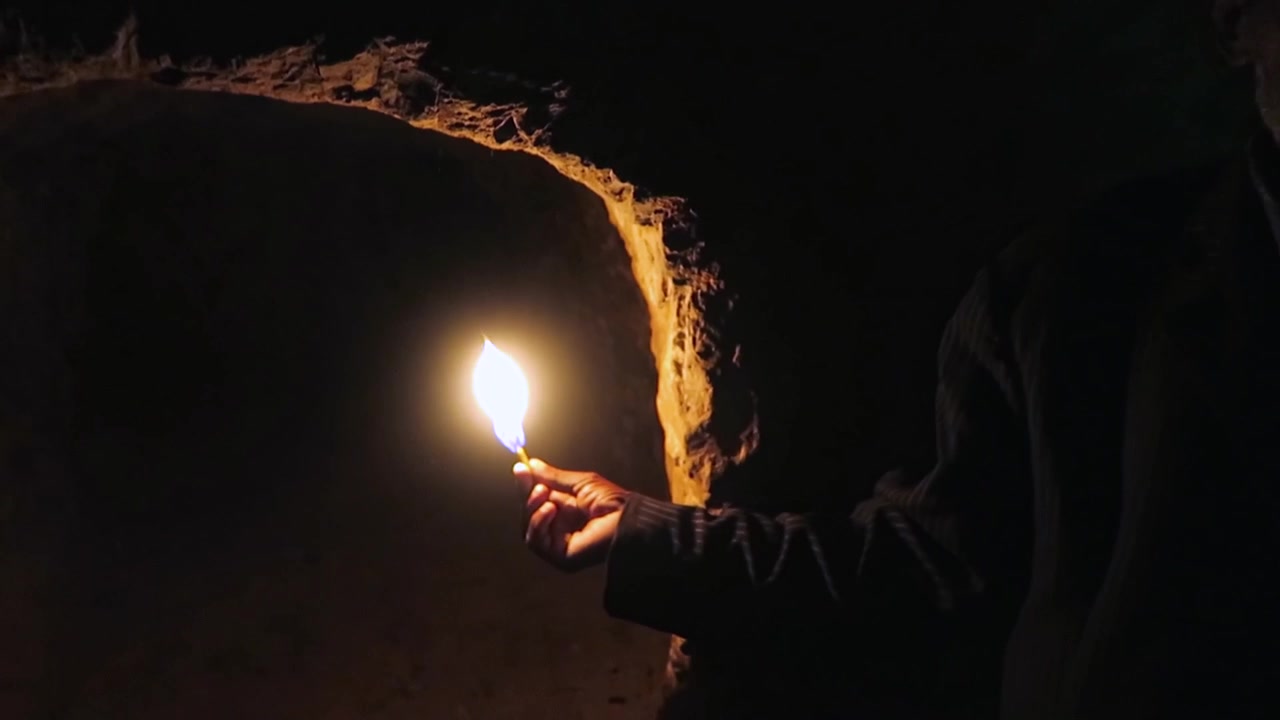 Uomo con una candela in un luogo buio