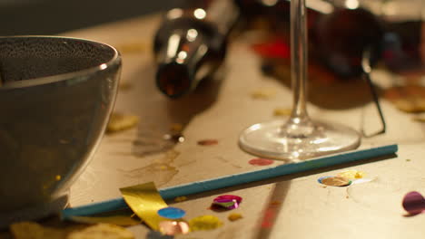 close up of messy table covered with empty wine glasses and beer bottles after house party