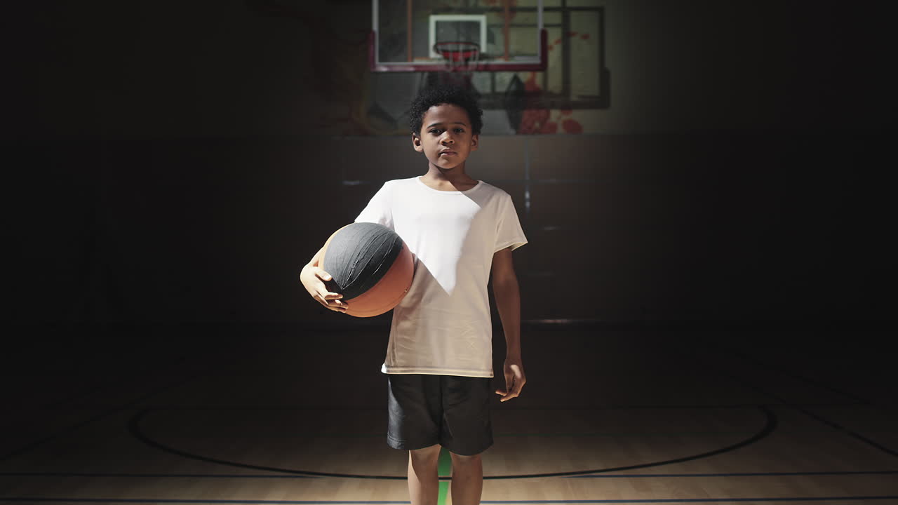 Boy Posing in Spotlight on Basketball Court