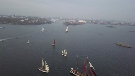 Aerial-footage-of-tradtional-wooden-sailing-ships-sailing-in-front-of-port-of-Helsinki-Finland