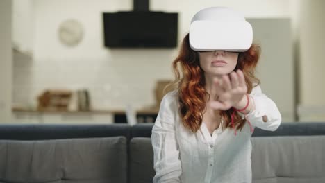 Serious-woman-sitting-on-sofa-in-vr-glasses.-Shocked-woman-looking-vr.