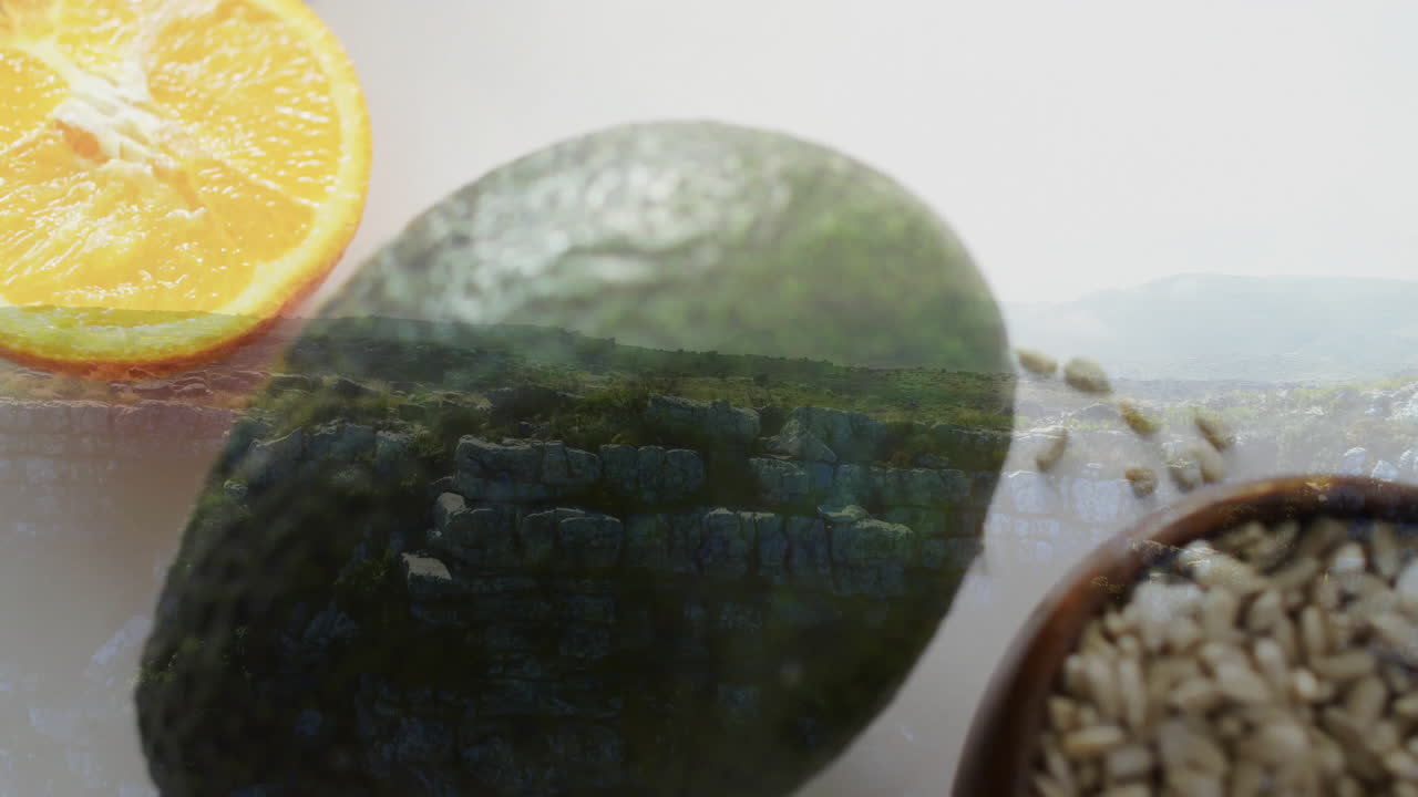 Animation of orange slice and avocado on grassy landscape with rocks