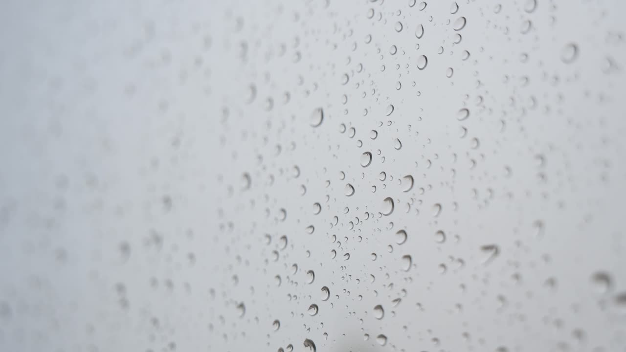 vista de enfoque estrecho de vidrio lluvioso a medida que las gotas de lluvia se ven en una ventana durante el clima sombrío y nublado