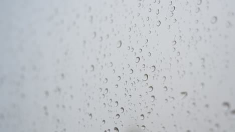 Narrow-focus-view-of-rainy-glass-as-rain-drops-are-seen-on-a-window-during-gloomy-and-overcast-weather