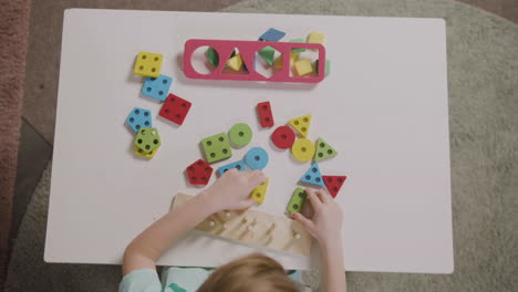 vista dall'alto della bambina che gioca con le forme che si impilano in una scuola montessori