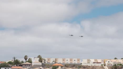 slow motion shot two military helicopters flying over residential area, porto santo