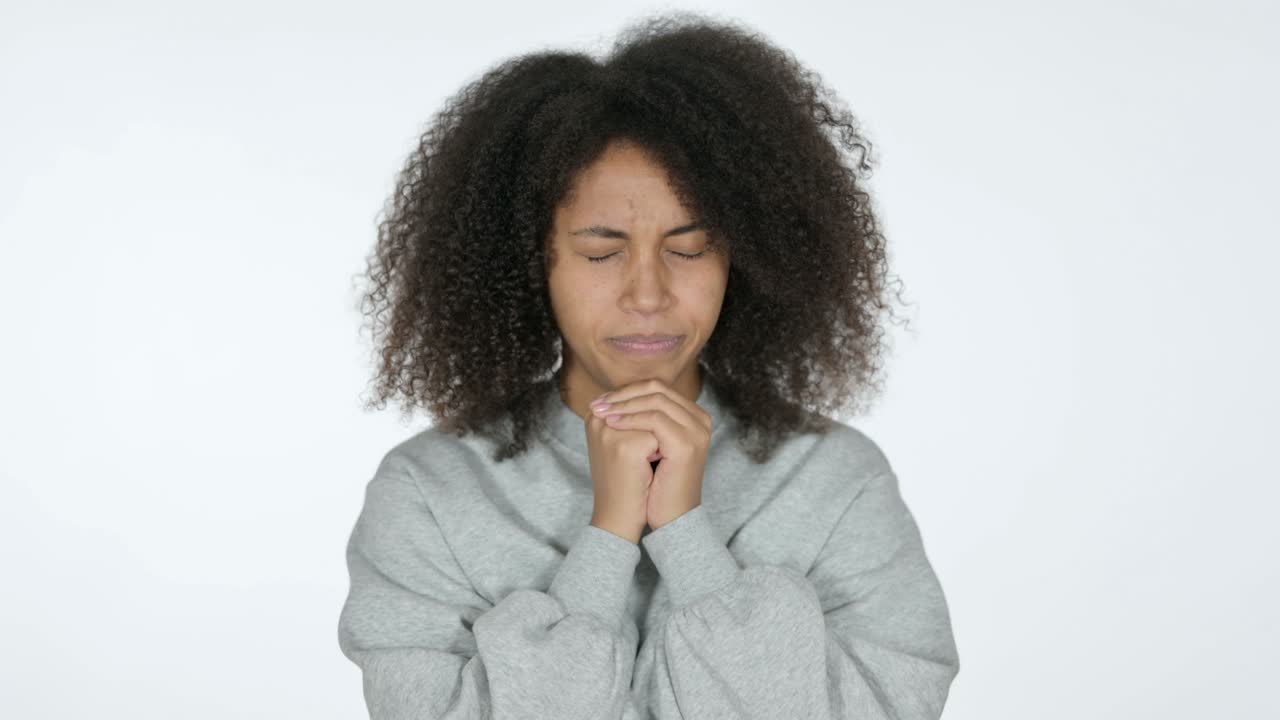 une jeune femme africaine pleine d'espoir prie, sur un fond blanc.