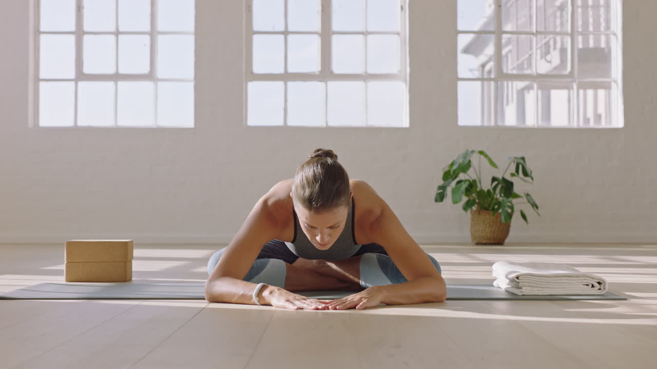 mujer de yoga saludable practicando pose fácil pose doblada hacia adelante disfrutando de un estilo de vida físico haciendo ejercicio en el estudio estirando un hermoso entrenamiento corporal en una colchoneta de ejercicios al amanecer