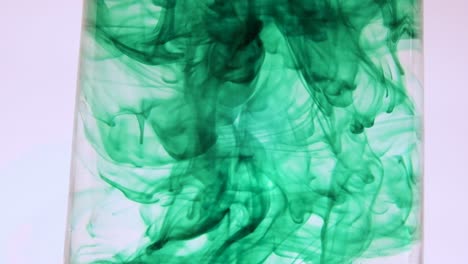 Green-food-coloring-swirling-in-a-glass-of-water-