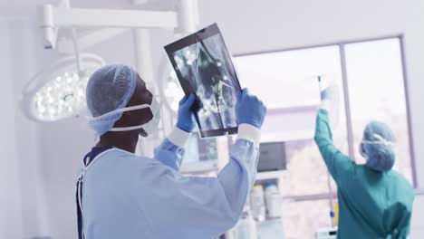 Video-Eines-Afroamerikanischen-Männlichen-Chirurgen,-Der-Röntgenaufnahmen-Im-Operationssaal-Untersucht,-Mit-Kopierraum