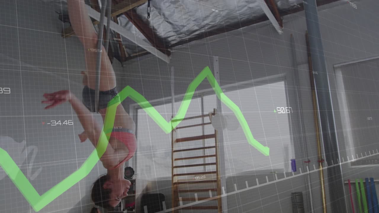 Afferrando un cerchio aereo, issando un istruttore di fitness capovolto che sincronizza il movimento con una sovrapposizione a griglia e un grafico verde.