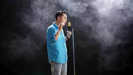 hombre cantando en el micrófono con fondo de humo