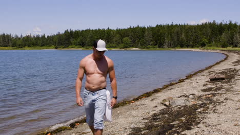 adulto, blanco, hombre sin camisa caminando por una playa de nueva inglaterra en una tarde de verano