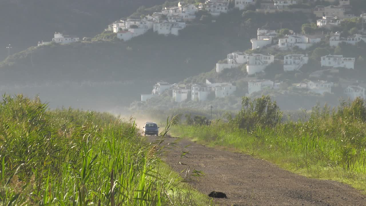 카메라를 향해 운전하는 시골의 먼지투성이 트랙에 있는 두 대의 자동차