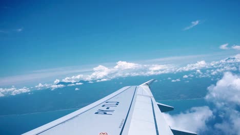 shot of the airplane wing taken from inside the plane while the it flies high above the clouds