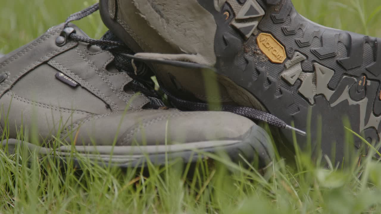 Pair of worn hiking shoes lying in a grass field
