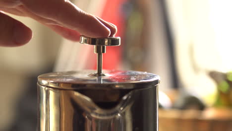 man presses a stainless steel french press