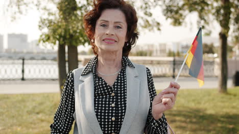 senior woman holding german flag in a park