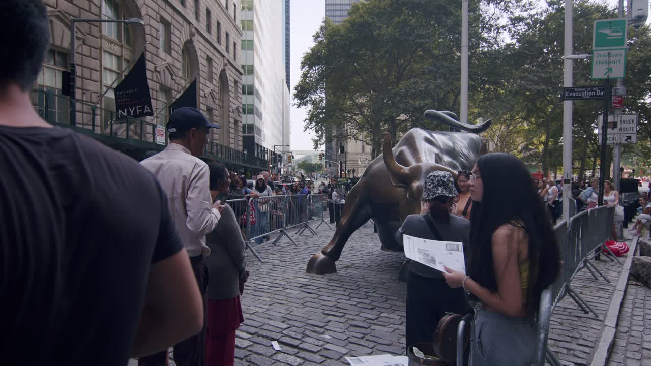 Tourists gather around the Charging Bull statue in New York City's Financial District on a sunny day