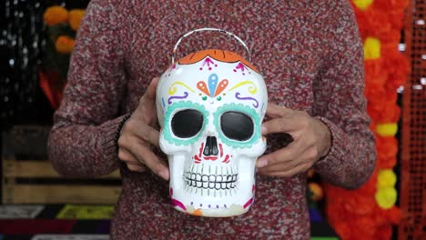 holding painted skull candy bucket for mexican día de los muertos