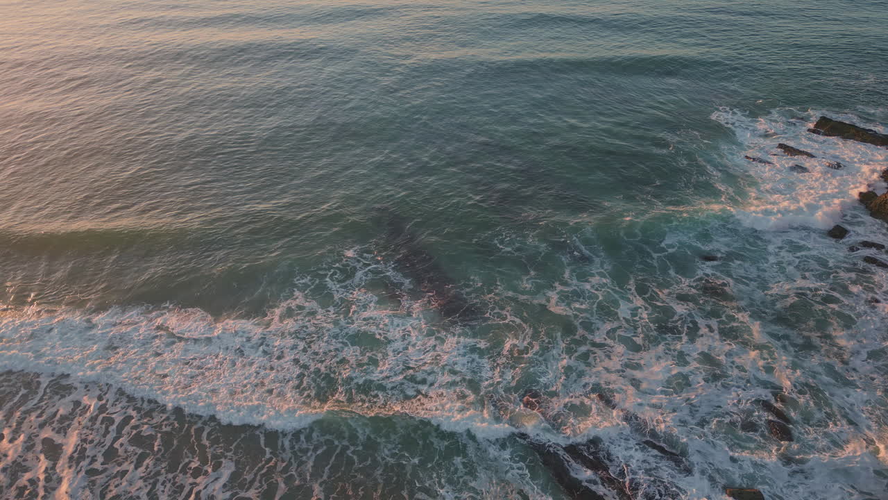 Veduta da drone di onde tempestose dell'oceano sulle scogliere rocciose alla luce del tramonto. Onde spumeggianti.