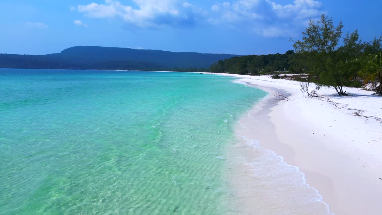 Sok San Beach with turquoise water washing the white sand, surrounded by palm trees and tropical vegetation. Nice aerial view flight static tripod hovering drone