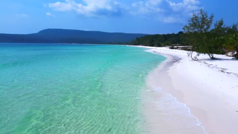 sok san beach with turquoise water washing the white sand, surrounded by palm trees and tropical vegetation. nice aerial view flight static tripod hovering drone