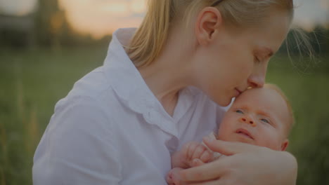 mother holding newborn at sunset