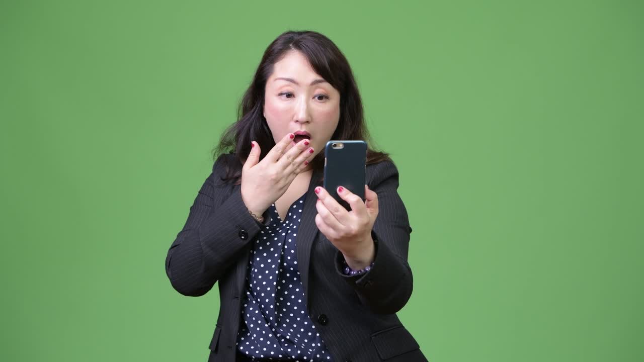 성숙 한 아름다운 아시아 사업가 여자 는 전화 를 사용 하는 동안 충격 을 느끼고 있다
