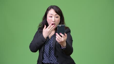 성숙 한 아름다운 아시아 사업가 여자 는 전화 를 사용 하는 동안 충격 을 느끼고 있다