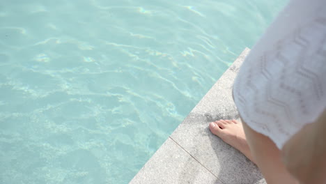 Feet-of-biracial-teenage-girl-standing-by-swimming-pool,-copy-space,-slow-motion