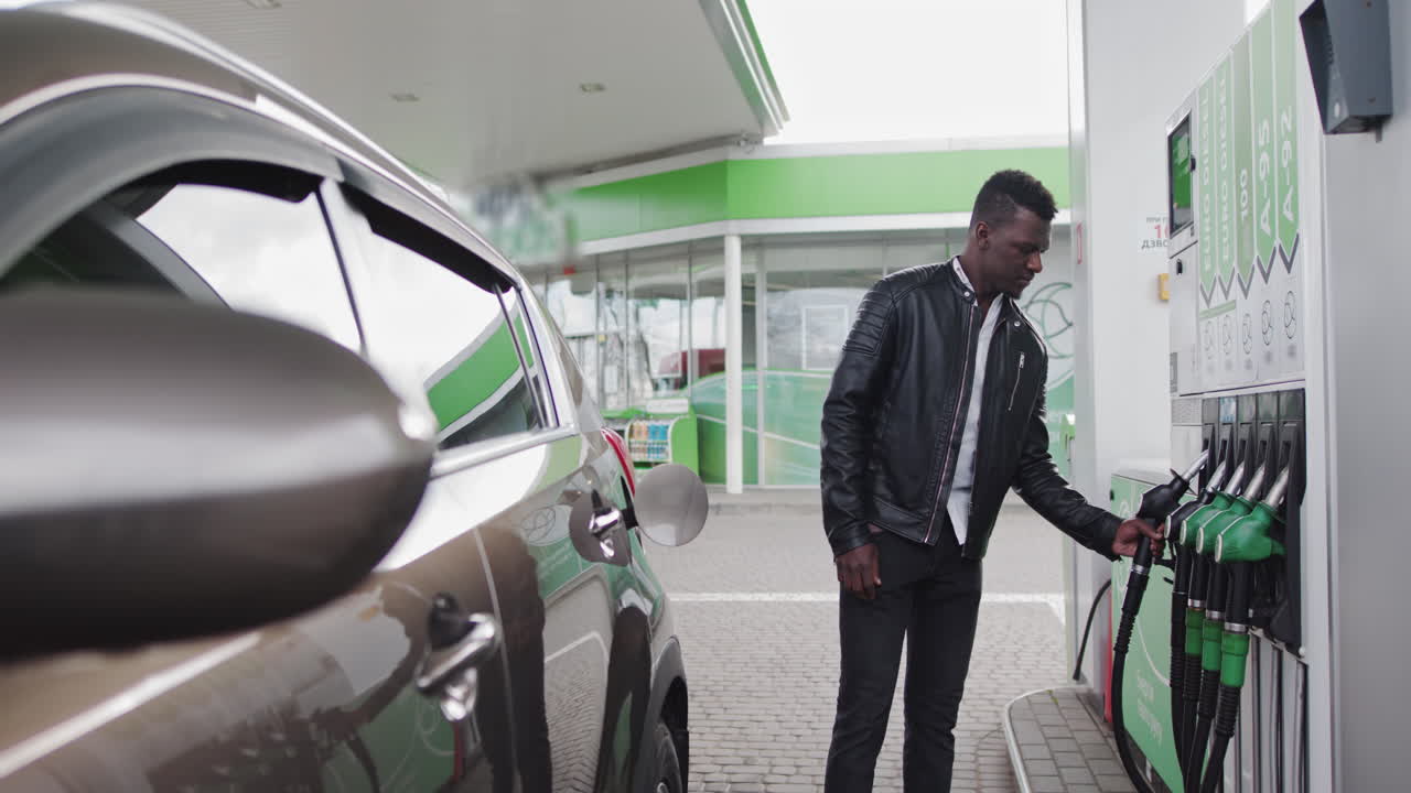 African american stylish man refueling car at gas station fuel nozzle getting put into its place