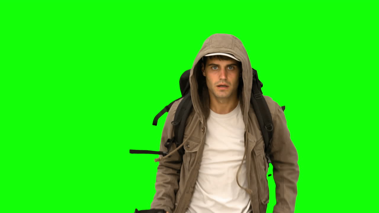 hombre con un abrigo y un bastón de senderismo corriendo en la pantalla verde