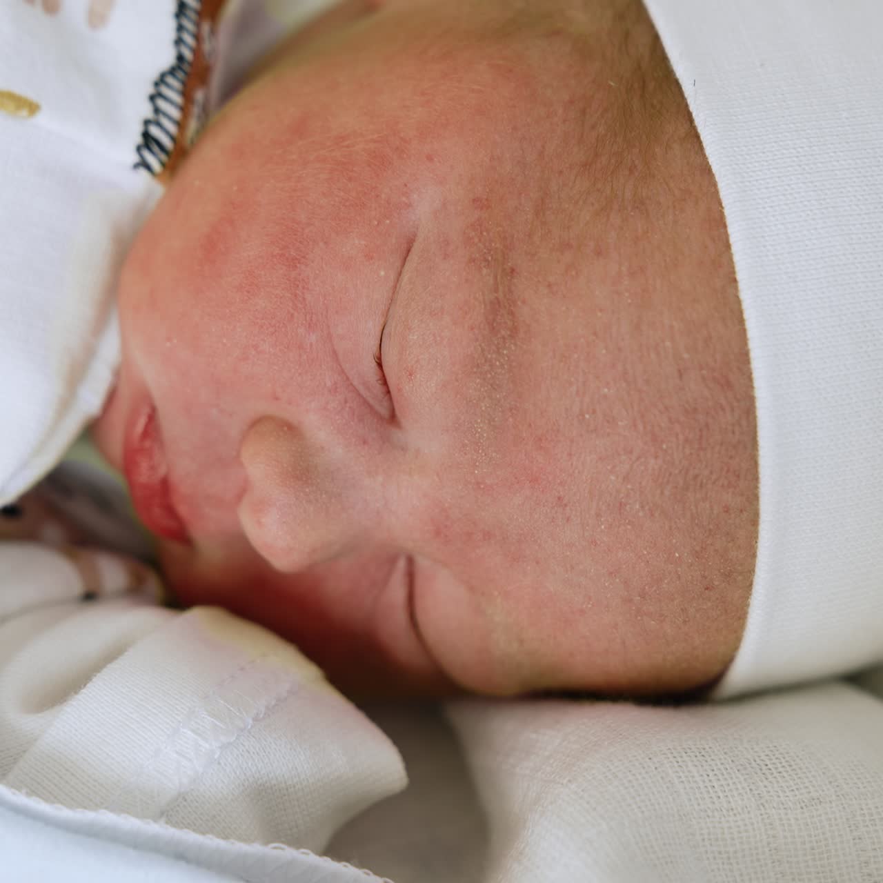 Il bellissimo viso di un neonato con un cappellino. Un bambino caucasico appoggia la testa rivolta verso la fotocamera. Primo piano