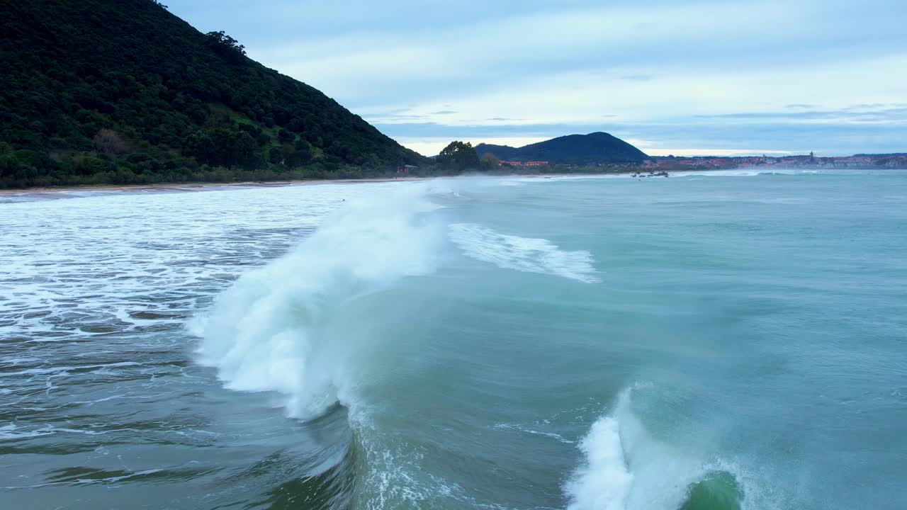серфер на веслах преодолевает большую волну в красивом синем море