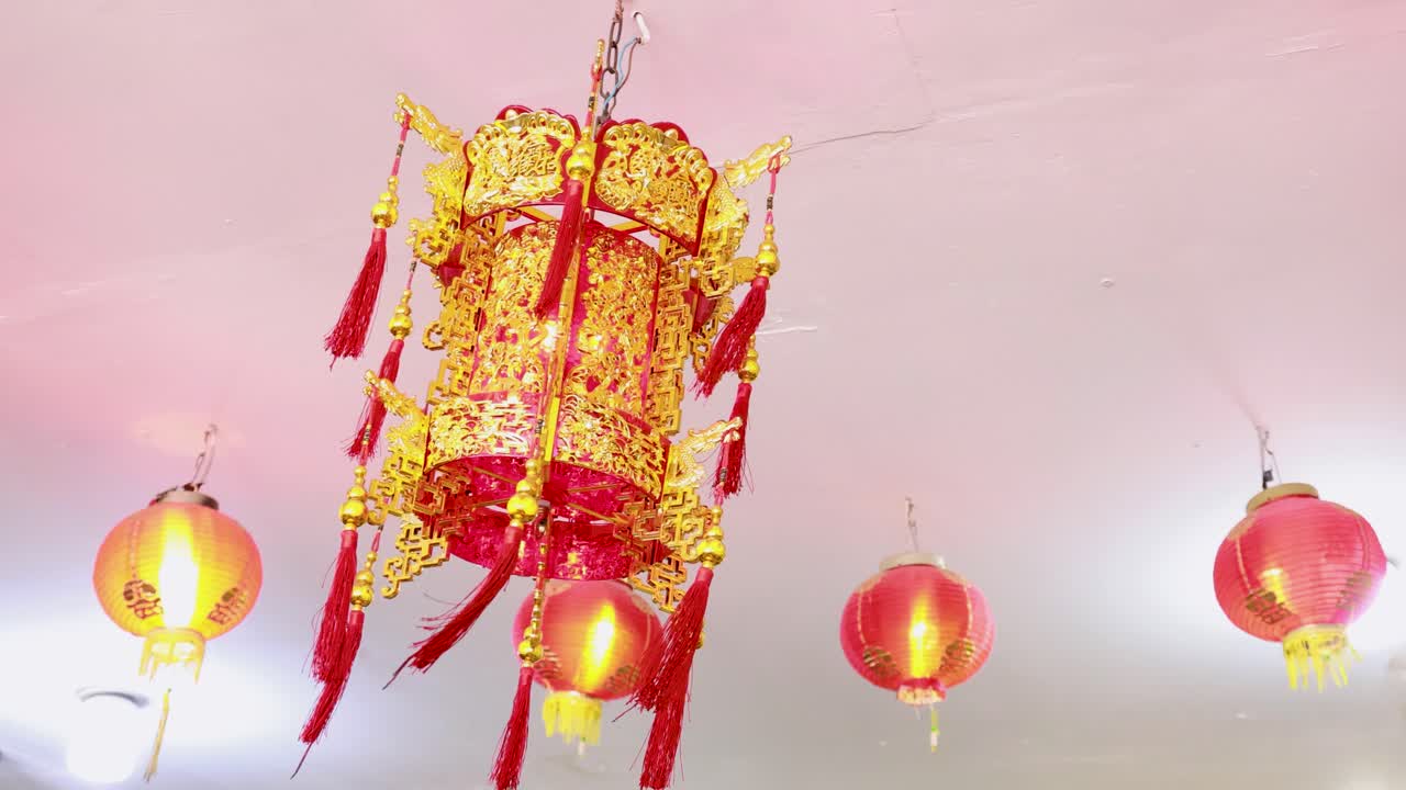 Red and gold lanterns gently sway in a festive setting, illuminated with soft lighting, capturing the essence of Chinese New Year in Phuket