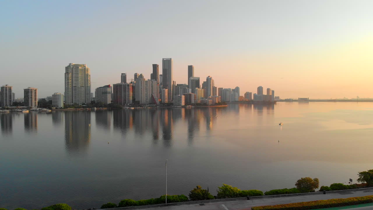 Rising drone shot over bikers and road and Miami skyline