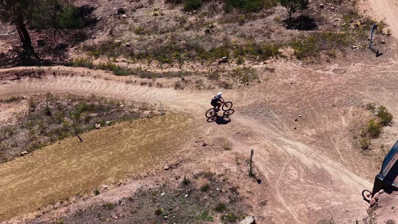 Ripresa aerea dall'alto segue un ciclista che pedala attraverso un parco arido della boscaglia australiana